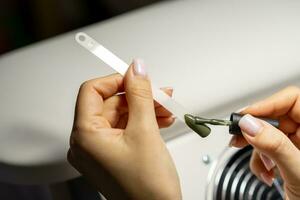 A manicurist applies gel nail polish to empty tips as a sample photo