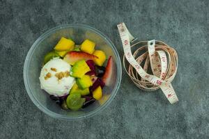 Fruit salad and fresh yogurt with white measuring tape. Healthy food for fitness. photo