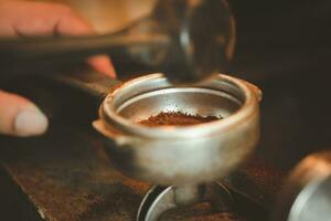 Professional male barista making an espresso shot, adding coffee powder into a portafilter. photo