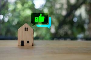 A wooden house placed on a table with thumbs up icon means real estate investment. photo