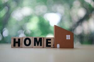 Wooden block with the word HOME and small wooden houses model photo