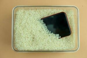 A smartphone is dried in raw rice for remove moisture in box photo