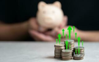 Interest rate and dividend concept. Symbol up arrow on stack of coin and man holding piggy bank photo
