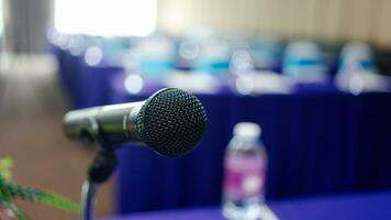 Microphone on the speaker table over the abstract blurred photo of the conference hall.