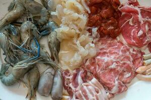conjunto de un surtido de ingredientes para shabu shabú, Fresco rebanado carne y mar comida foto