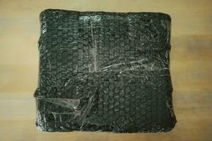 Black bubble wrapped with adhesive tape for packing fragile items. Safe delivery. photo