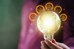 Man holding a bright light bulb with a strategy icon. Concept of great inspiration and innovation new beginning. photo