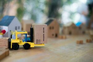 Forklift truck with a miniature cardboard box shopping online with the blurred model home background. photo