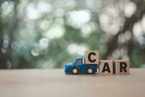 Toy blue pickup truck carries a wooden text car. photo