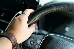 Man hands holding on to the wheel of a new car photo