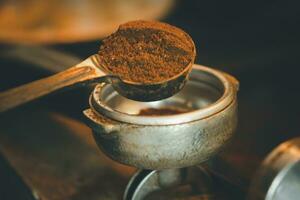 Professional male barista making an espresso shot, adding coffee powder into a portafilter. photo