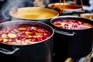 Beverages fruits and berries hot mulled wine in pots with steam in street food market. Generative AI photo