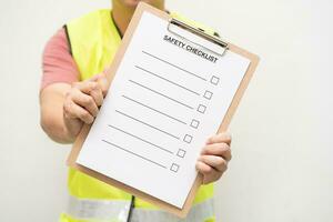 Staff holding blank checking on safety checklist form. Hand of staff is using the safety checklist sheet to verify working condition in isolated background. photo