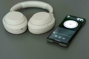 Music player on screen of mobile phone and wireless headphone. Selective focus. isolated on gray background. photo