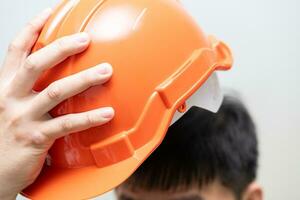 A man wearing orange hard hat helmet or safety helmet. Protect your head, always wear your hard hat. photo