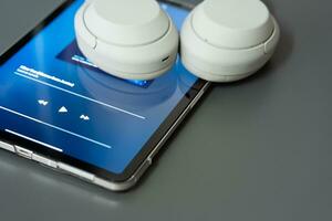 Music player on screen of mobile phone and wireless headphone. Selective focus. isolated on gray background. photo