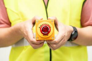 Engineer pressing an emergency stop button with copy space. Industrial working operating process. Stop Switch machine malfunctioning for safety. photo