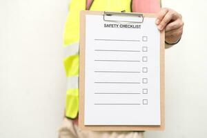 Staff holding blank checking on safety checklist form. Hand of staff is using the safety checklist sheet to verify working condition in isolated background. photo