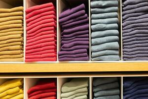 colección de vistoso algodón calcetines en estantería en tienda. multicolor calcetines apilado en el estante. con oscuro tono. foto