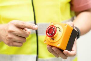 Engineer pressing an emergency stop button with copy space. Industrial working operating process. Stop Switch machine malfunctioning for safety. photo