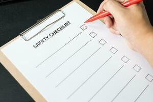 Blank checklist paper during safety audit and risk verification. safety checklist form on the desk with red pen. photo