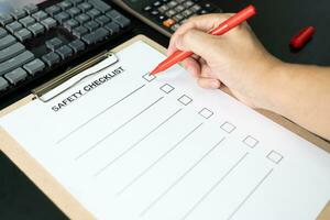 Blank checklist paper during safety audit and risk verification. safety checklist form on the desk with red pen. photo