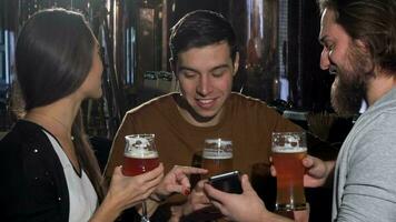 grupo do amigos tendo Diversão às Cerveja bar, usando inteligente telefone juntos video