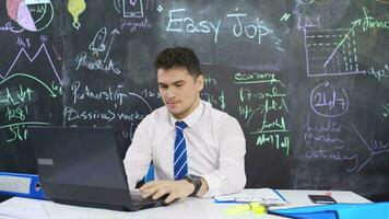 Businessman writes easy on blackboard and ties arm. video