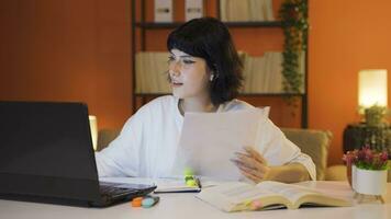 Female student working between paper and laptop. video