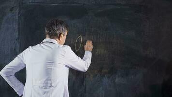 Male doctor writing Oncology on the blackboard. video