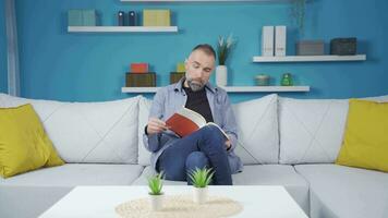 homme en train de lire une livre et en pensant dans étonnement. video