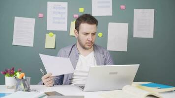 Male student working between paper and laptop. video