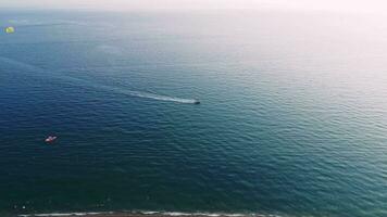 zonsondergang over- oceaan golven wassen zand strand. speedboot Aan de zonsondergang zee. 4k video