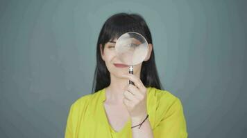 Woman looking at camera with magnifying glass. video