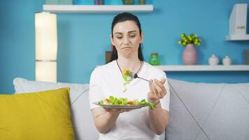 Person looking at vegetable on fork with unhappy expression. Difficulty dieting. video