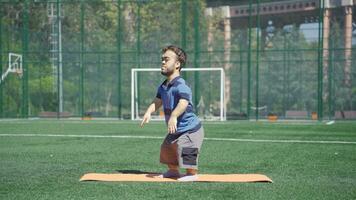 nain Jeune homme squat dans le parc. nain Jeune homme est faire de l'exercice. video