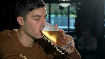 attrayant homme sirotant délicieux Bière de le sien verre, relaxant à le bar video