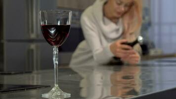 rosso vino nel un' bicchiere su il tavolo, donna Tenere un' bottiglia su il sfondo video