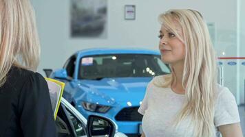 Beautiful woman talking to the salesperson at cars dealership salon video