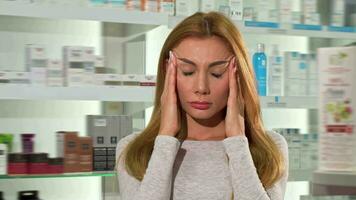 Gorgeous young woman suffering from headache at the drugstore video