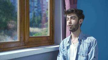 el hombre en frente de el ventana, tomando un profundo aliento y clausura su ojos. video