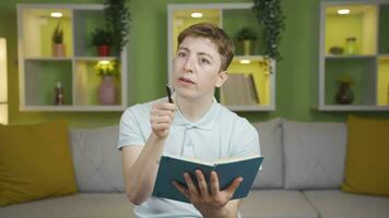 Young man at home taking notes, planning and analysis looking at camera. video