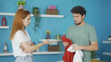 The man tries on clothes at home and his wife helps him. video