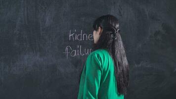 Woman with kidney failure writing on blackboard looks at camera helpless and suffering. video