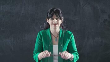 Woman writing visual impairment on blackboard looks at camera. video