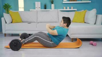 Obesity boy doing sit-ups at home, interested in sports. video