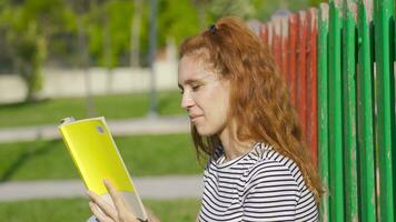 jovem mulher lendo uma livro dentro a parque. video