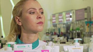 fêmea farmacêutico organizando produtos em uma prateleira, trabalhando às farmácia video