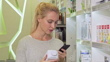 hembra utilizando inteligente teléfono, hojeada información en línea mientras compras medicación video