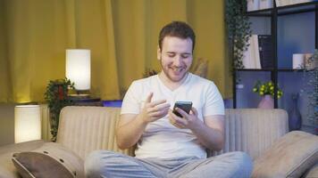 Man using social media on phone laughing at night at home. video